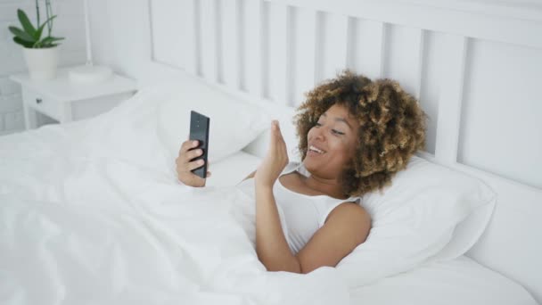 Lachende vrouw in bed praten online — Stockvideo
