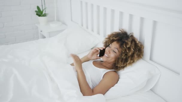 Tartalom nő beszél telefonon az ágyban — Stock videók