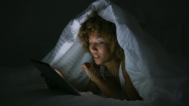 Mulher usando comprimido sob cobertor — Vídeo de Stock