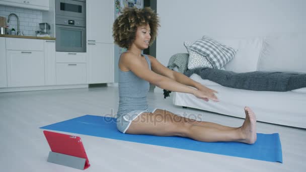 Content woman training yoga with device — Stock Video