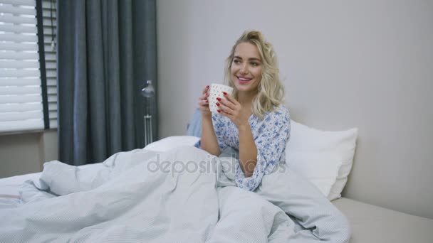 Прекрасная женщина, пьющая в постели — стоковое видео