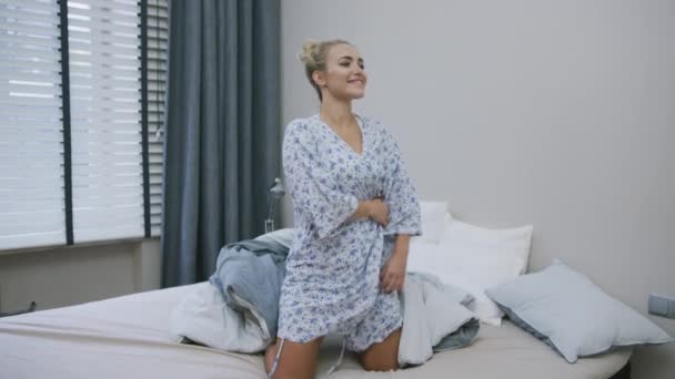 Женщина в рубашке стоит на кровати — стоковое видео