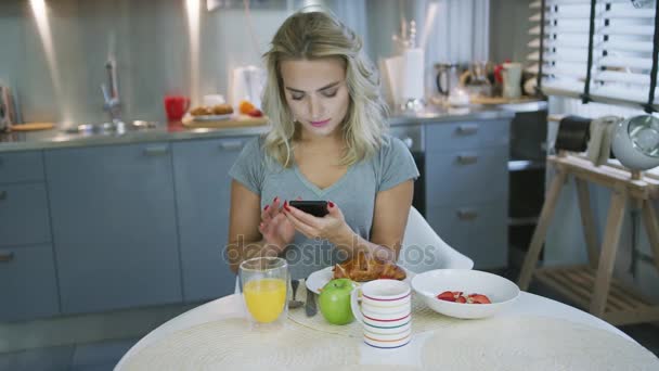 Vrouw met behulp van de smartphone tijdens het ontbijt — Stockvideo