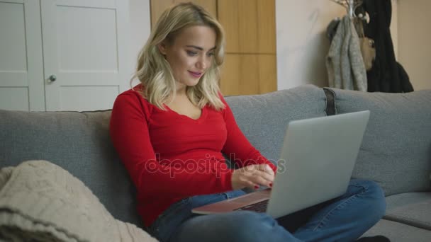 Gülümseyen kadın kanepede dizüstü bilgisayar kullanarak — Stok video