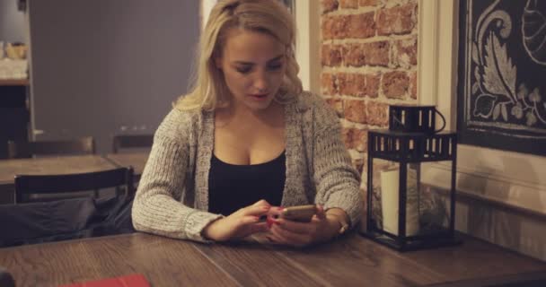 Woman using smartphone at table — Stock Video