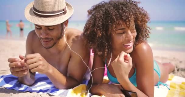 Casal deitado com música na praia — Vídeo de Stock