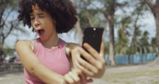 Laughing young girl taking selfie in park — Stock Video