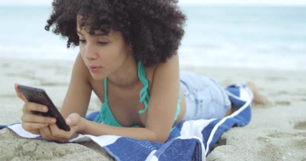 Mujer usando el teléfono mientras se enfría en la arena — Vídeo de stock