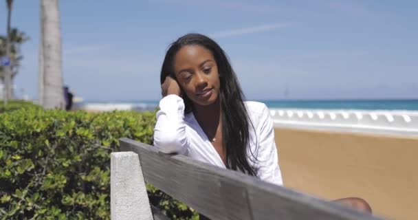 Attraktive junge Frau sitzt auf Bank am Meer — Stockvideo