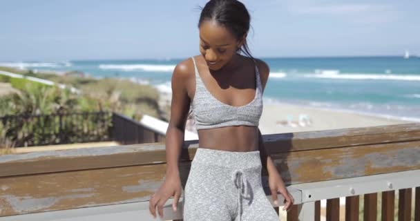 Alegre mujer deportiva en la cerca en la playa — Vídeos de Stock