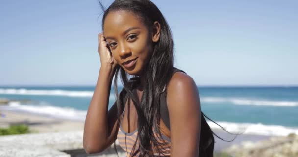 Smiling young woman sitting at ocean — Stock Video