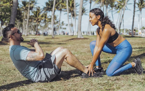 Жінка допомагає чоловікові з фізичними вправами в парку — стокове фото