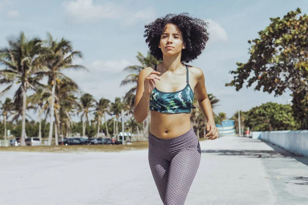 Chica negra en forma trotando en el paseo marítimo tropical — Foto de Stock