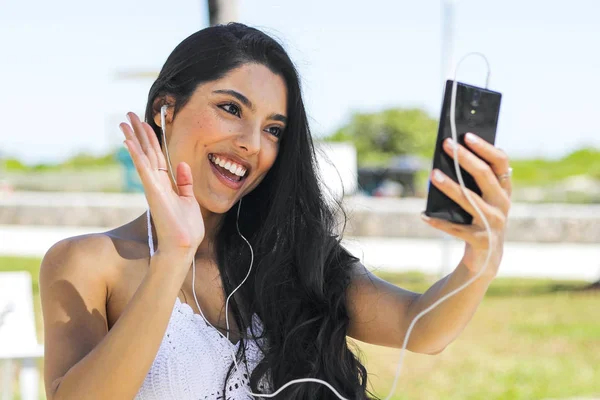 Naurava tyttö chattailu verkossa puhelimen kanssa puistossa — kuvapankkivalokuva