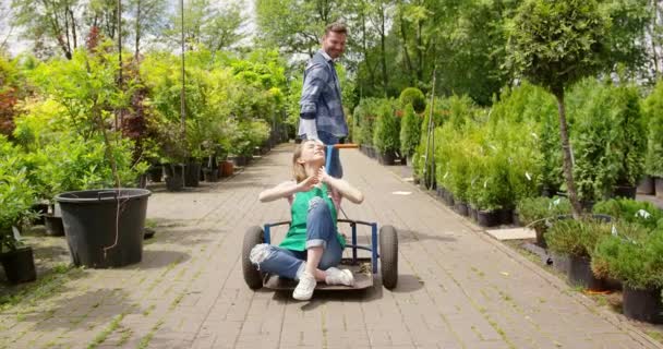 Contenido hombre cabalgando chica en el carrito en el jardín — Vídeos de Stock