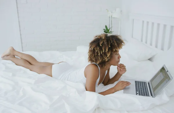 Jolie femme se prélasser sur le lit avec ordinateur portable — Photo