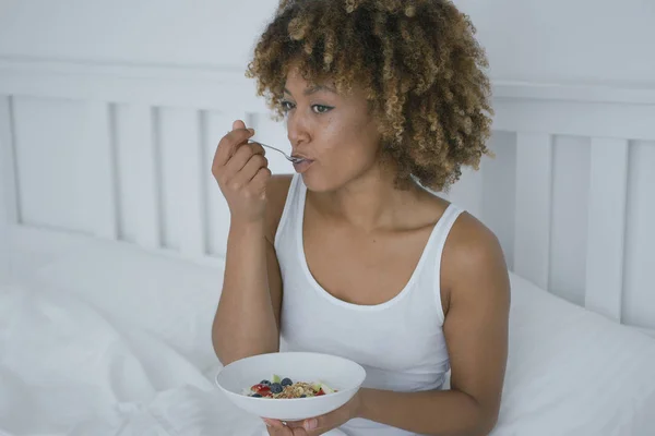 Young woman eating breakfast in bed — Stock Photo, Image