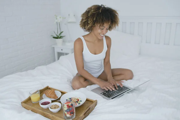 Mujer de contenido con ordenador portátil y desayuno — Foto de Stock