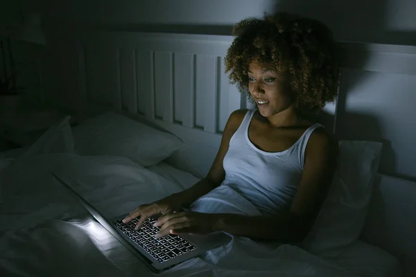 Mladá žena pomocí přenosného počítače v noci — Stock fotografie