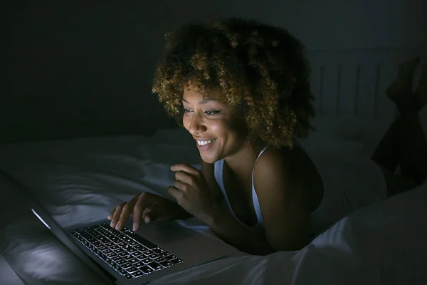 Mujer sonriente charlando con el ordenador portátil en la oscuridad — Foto de Stock