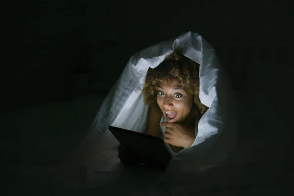Vzrušená žena pod dekou s tabletem — Stock fotografie