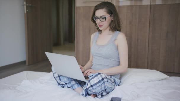 Femme en pyjama utilisant un ordinateur portable dans la chambre — Video