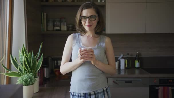 Donna sorridente in piedi in cucina in possesso di tazza — Video Stock