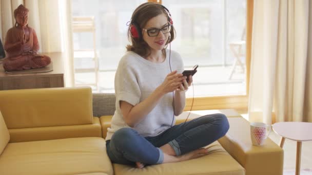 Barefoot vrouw luisteren naar muziek op de sofa — Stockvideo