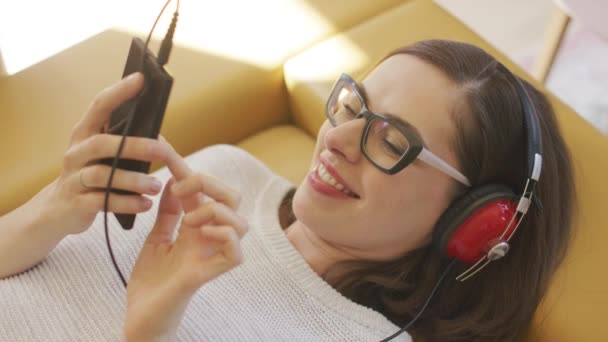 Wesoły Kobieta, słuchania muzyki i przeglądania smartfonem — Wideo stockowe