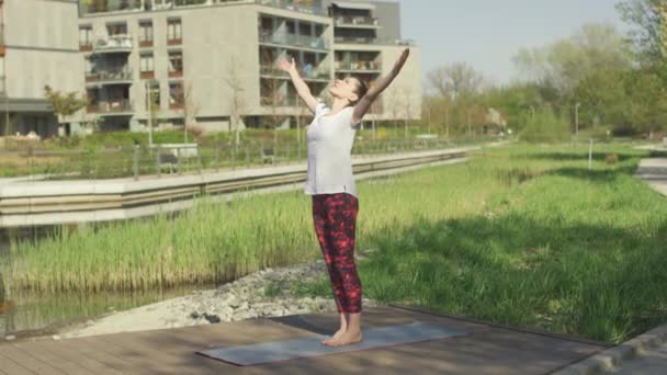 Підходить молода жінка тренує йогу позу на килимку — стокове відео