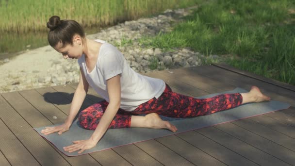 Молодая женщина делает упражнения йоги на коврике в летний день — стоковое видео