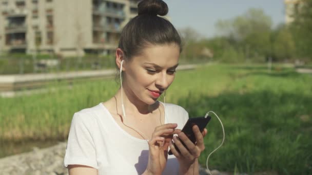 Junge Brünette im Kopfhörer mit Smartphone — Stockvideo