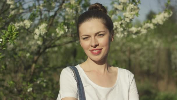Lächelnde schöne Frau in der Nähe blühender Bäume — Stockvideo