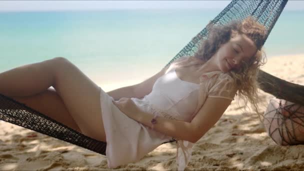 Charming woman fantasying lounging in hammock on beach — Stock Video