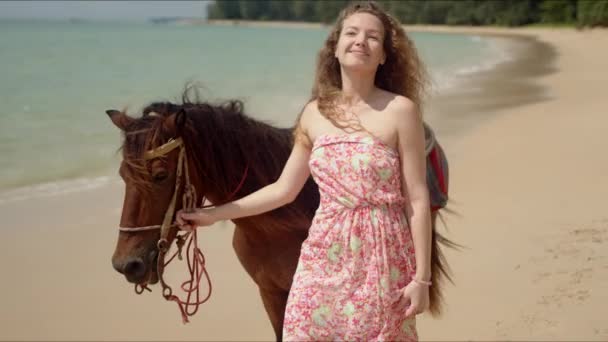 海辺の花嫁の下で強力な従順な馬をリードするリラックスした女性 — ストック動画