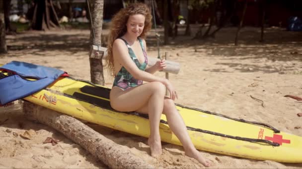 Active woman in swimsuit sitting on yellow swimboard — Stock Video