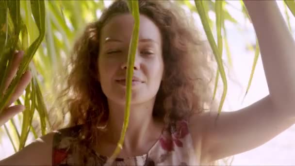 느긋 한 여자가 야자나무 잎 뒤에서 있다 — 비디오