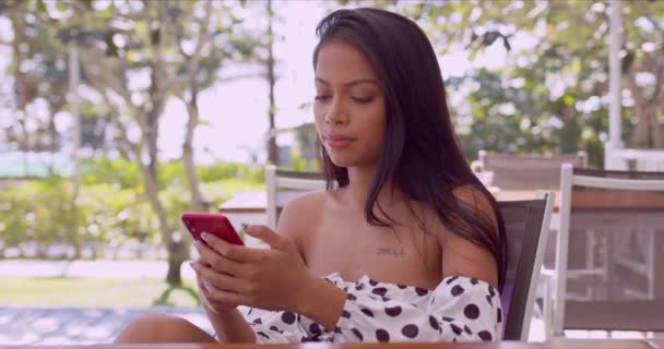 テラスで休んでいる間にスマートフォンと対話する幸せな民族の女性 — ストック動画