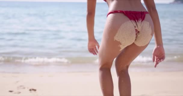 Woman with sand on buttocks standing on beach — Stock Video