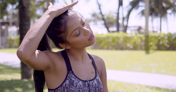 Tired Asian woman rubbing head with closed eyes in park — Stock Photo, Image