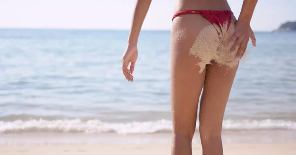 砂浜に立ってお尻に砂を持つ女性 — ストック写真