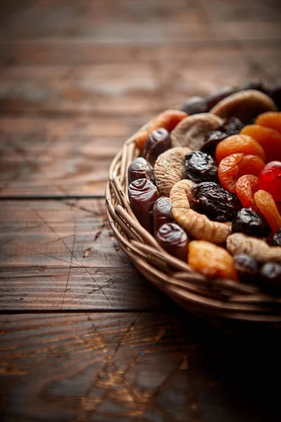 Meng van gedroogde vruchten in een kleine rieten mand op houten tafel — Stockfoto