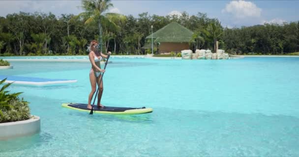 Mujer flotando sobre tabla de paddle en gran piscina — Vídeos de Stock