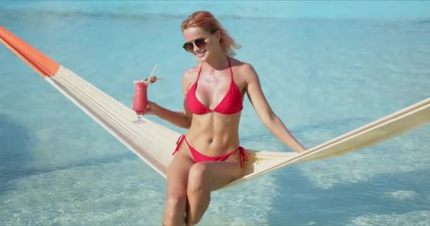 Femme joyeuse avec cocktail assis sur hamac près de la piscine — Video