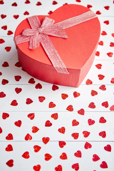 盒装礼物放置在白色木桌上的心形红色亮片 — 图库照片