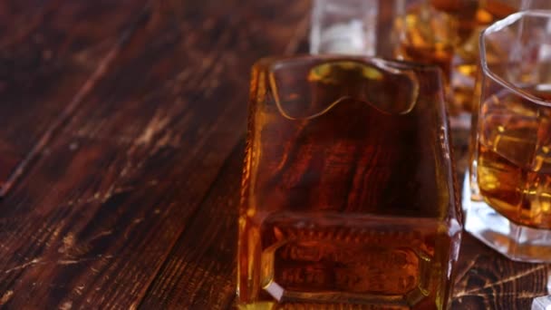 Bottle of whiskey with two glasses placed on rustic wooden table — Stock Video