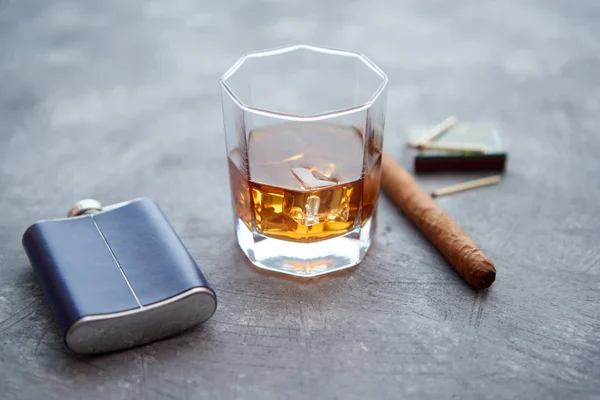 Vaso de whisky con hielo, cigarro cubano grande, cerillas y frasco de cadera — Foto de Stock