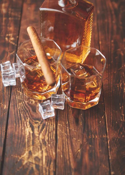 Butelka whisky z dwoma szklankami i kubańskim cygarem na drewnianym stole — Zdjęcie stockowe