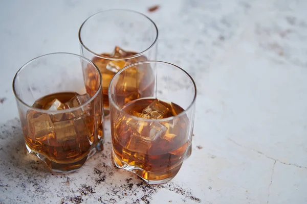 Tres vasos llenos de cubitos de hielo y whisky aromático viejo — Foto de Stock