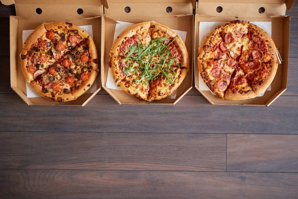 Trzy różne rodzaje pizzy w skrzynkach dostawczych — Zdjęcie stockowe